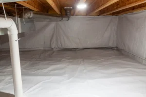A clean, empty basement features insulation and white plastic sheeting on walls and floor, resembling a professional crawlspace encapsulation service. Exposed wooden beams line the ceiling alongside visible ductwork.